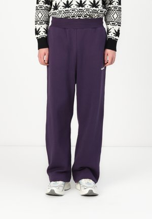 Pantaloni della tuta viola con vestibilità rilassata, realizzati in tessuto morbido. Presentano un ampio elastico in vita e un piccolo logo laterale.