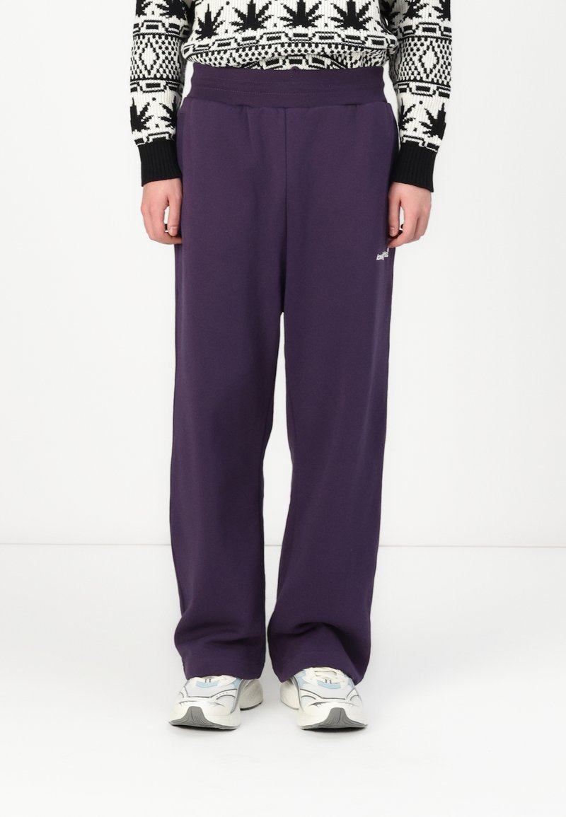 Purple sweatpants with a relaxed fit, made of soft fabric. Features a wide waistband and small logo detail on the side.