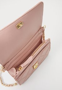 Quiltad rosa konstläder handbag med gulddetaljer, utrustad med en kedjestropp, en dragkedjeficka och flera fack för organisering.