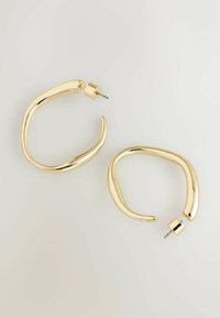 Goldene Creolen mit einem glatten, geschwungenen Design. Sie verfügen über eine polierte Oberfläche und einen Steckverschluss, der eine schlanke, moderne Form zur Geltung bringt.