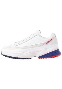 Vit atletisk sneakers med ovandel i mesh och mocka, flerfärgad tjock sula med röda, blå och svarta accenter, snörning och varumärkesdetalj.