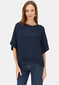 Granatowy krótki top z krótkim rękawem o luźnym kroju, z okrągłym dekoltem i teksturowanym dołem, zestawiony z ciemnoniebieskimi dżinsami. Gładka tkanina, minimalistyczny design.