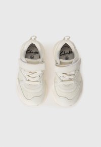 Valged sneakersid, mille külgedel on tekstureeritud meshtaru muster, millel on Velcro riba ja paelad, pehme kangasvooder ja kummist tallad.