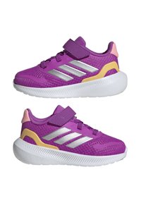 Fioletowe buty sportowe z siateczkową cholewką, srebrnymi paseczkami, żółtymi i różowymi akcentami, wyściółką wokół kostki oraz białą gumową podeszwą z teksturowanym bieżnikiem.