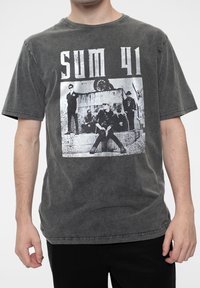 Gray cotton T-shirt featuring a distressed crew neck, short sleeves, and a large black-and-white graphic of a band on the front.