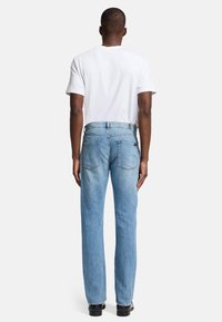 Blaue Denim-Jeans mit geradem Bein, mittelhoher Taille, Gesäßtaschen und einem gewaschenen Finish. Kombiniert mit einem schlichten weißen T-Shirt.