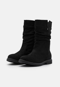 Bottes chelsea en cuir suédé noir avec un design drapé, semelle en caoutchouc texturé et un détail décoratif à pression. Fini lisse sur le dessus avec un tige ajustée.