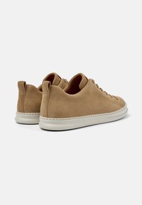 Sneaker in suede di colore beige chiaro con profilo basso, bordi arrotondati, design con lacci e suola in gomma bianca.
