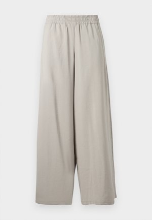 Pantaloni beige chiaro a gamba larga con vita elasticizzata, vestibilità ampia e orlo alla caviglia, mostrati su uno sfondo bianco.
