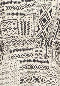 Motif tribal géométrique noir et blanc avec des zigzags, des losanges et des lignes sur fond de tissu.