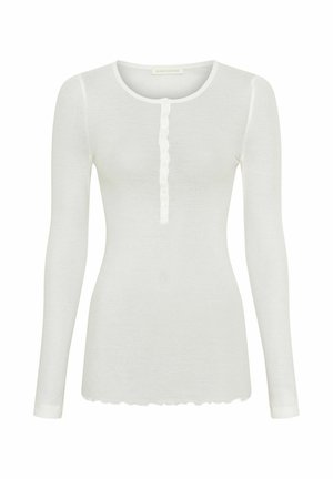 Camicia bianca a maniche lunghe in tessuto morbido con scollatura rotonda, dotata di una fila di bottoni sul fronte e orlo scalloppato.