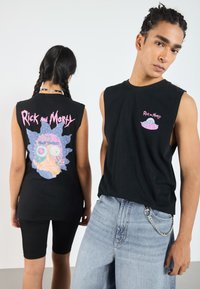 Schwarze ärmellose T-Shirts mit bunten "Rick and Morty" Grafiken auf der Vorder- und Rückseite, kombiniert mit hellblauen Jeans und schwarzen Shorts.
