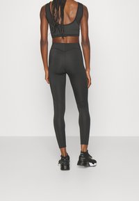 Top corto atlético negro y leggings de tiro alto hechos de una tela suave y elástica. Presenta un diseño de espalda nadadora y costuras ligeras.