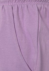 Tissu en coton lilas avec taille élastique, détail froncé et couture de poche latérale, offrant une texture lisse et une finition soignée.