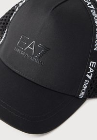 Μαύρο καπέλο EA7 Emporio Armani με πίσω πάνελ από δίχτυ, λευκό κείμενο με το λογότυπο κατά μήκος των πλευρών και ανάγλυφο σήμα στο μπροστινό πάνελ.