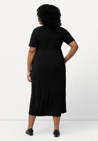 Vestido negro midi con mangas cortas, cintura elástica para un ajuste relajado, tela suave y un diseño simple. Acentuado con un respaldo plisado.