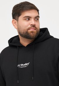 Zwarte hoodie van een katoenmix, met een logo-print aan de voorkant en verstelbare trekkoorden. Soepele textuur en klassiek ontwerp.