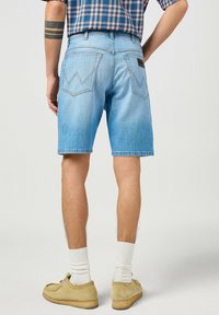 Shorts in denim azzurro chiaro con vestibilità comoda, caratterizzati da due tasche posteriori con cuciture a zigzag e un timbro in pelle vicino alla vita.