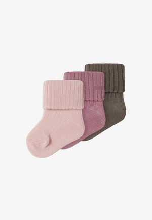 Trois chaussettes épaisses en tricot pour bébé en rose pâle, vieux rose et marron, chacune avec un revers plié, disposées en chevauchement sur un fond blanc.
