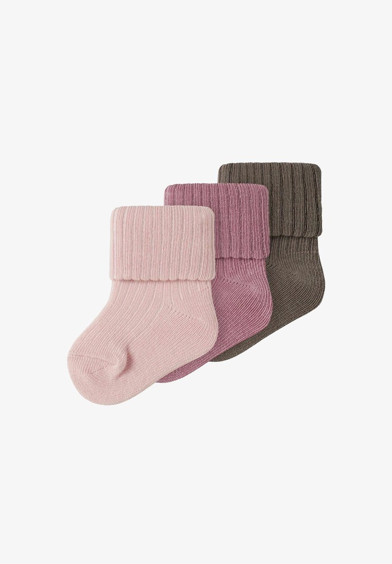Trois chaussettes épaisses en tricot pour bébé en rose pâle, vieux rose et marron, chacune avec un revers plié, disposées en chevauchement sur un fond blanc.