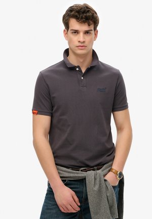 Dark gray polo shirt with a textured fabric, two-button placket, embroidered logo on the chest, and an orange accent on the sleeve.