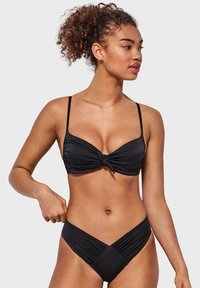 Conjunto de bikini negro que incluye un top con nudos, tirantes ajustables y una parte inferior de cintura alta con textura fruncida y un frente en forma de V.