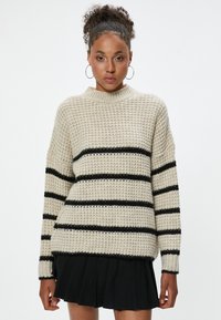 Strickpullover in Beige mit schwarzen horizontalen Streifen, mit hohem Kragen und lockerer Passform. Strukturiertes Gewebe mit gerippten Bündchen.