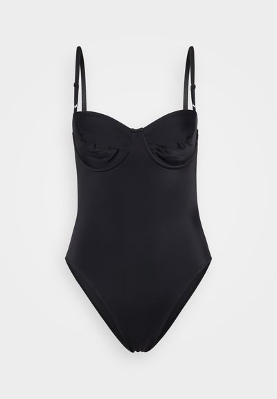 Mustavärviline ühes tükis ujumisriietus, millel on reguleeritavad rihmad, vooderdatud tassid ja sile, tekstuuriga kangas. Ei sisalda nähtavaid mustreid ega kuvandeid.