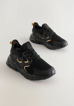 Czarne sportowe sneakersy z siateczkową cholewką, złotymi akcentami, fakturowaną powierzchnią, grubą podeszwą z nakrapianym wzorem oraz sznurowanym przodem.