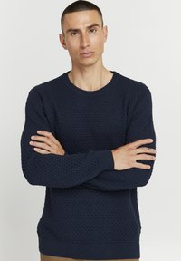 Pulover tricotat texturat de culoare bleumarin, cu guler rotund și manșete ribbate, având un model de fagure pe toată suprafața.