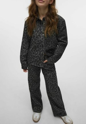 Ensemble en denim noir avec un motif léopard, comprenant une chemise à boutons et un pantalon large, le tout associé à des baskets blanches.