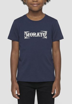 Enfant portant un t-shirt Morato bleu marine et un pantalon noir, debout avec les bras détendus devant un fond uni.