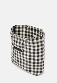 Strukturovaná taška přes rameno s černobílým kostkovaným vzorem, textilní materiál, stříbrné doplňky a černá akcentová rukojeť.