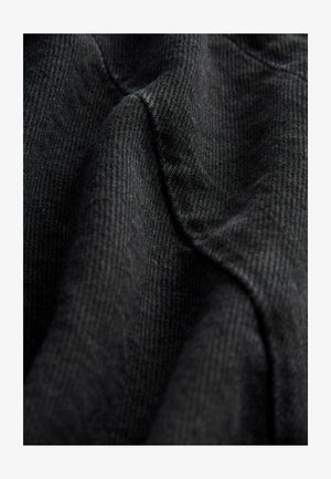 Tela negra texturizada con un patrón tejido, que muestra líneas suaves y lisas y un leve brillo, drapeada para resaltar contornos y profundidad.