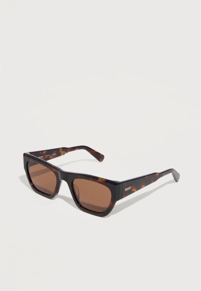 Ορθογώνια γυαλιά ηλίου tortoiseshell με καφέ φακούς και το λογότυπο "QUAY" στον βραχίονα, τοποθετημένα σε λευκή επιφάνεια.