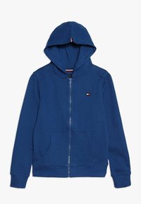 Felpa blu con zip, tasca frontale, cappuccio con coulisse e piccolo logo ricamato sul petto. Realizzata in un morbido tessuto testurizzato.