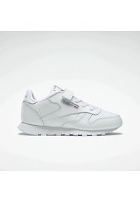 Zapatilla deportiva blanca con parte superior de cuero, parte frontal con cordones y tira de velcro. Presenta un cuello acolchado, paneles laterales texturizados y suela de goma.
