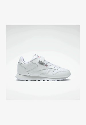 Zapatilla deportiva blanca con parte superior de cuero, parte frontal con cordones y tira de velcro. Presenta un cuello acolchado, paneles laterales texturizados y suela de goma.