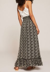 Czarna maxi spódnica w kwiaty z falbaną, wykonana z lekkiego materiału. W zestawie z białym topem na cienkich ramiączkach.