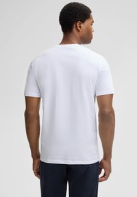 Witte t-shirt met korte mouwen en ronde hals, gemaakt van zachte katoenen stof. Heeft een subtiele textuur en een logo op de onderrug.