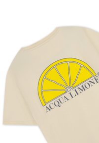 Beige bomull t-shirt med en stor grafisk av en gul citronskiva och texten "ACQUA LIMONI" i mörkblått nedan.