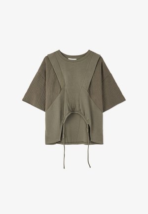 Maglietta oversize verde oliva con maniche corte, caratterizzata da dettagli a coste e una vita cinchata con lacci. Tessuto morbido e texture.