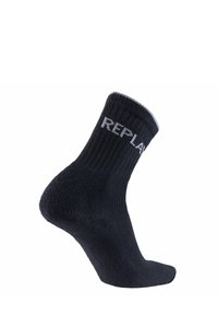 Chaussettes noires en coton jusqu'à la cheville avec une texture côtelée et un logo blanc "REPLAY" sur le revers. Comprend un talon et un orteil renforcés.