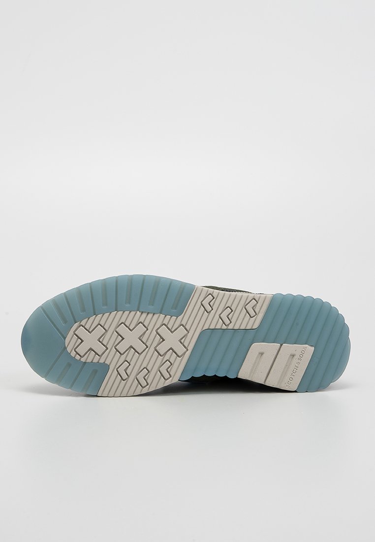 Podeszwa buta charakteryzuje się teksturowaną, jasnoniebieską gumową podeszwą z szarym śródpodeszwą. Wzór obejmuje wypukłe kształty geometryczne oraz detale z logo.