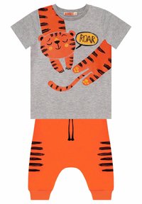 Szary t-shirt z pomarańczowymi grafikami tygrysa i dymkiem "ROAR", w połączeniu z pomarańczowymi spodniami z czarnymi paskami tygrysa i sznurkiem do regulacji.