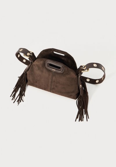 Sac à main en suède marron avec des accents en franges. Présente une forme structurée, deux poignées avec un matériel circulaire et un compartiment supérieur ouvert.