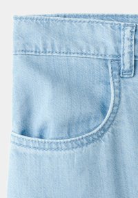 Lichtblauwe denimstof die de voorzak, de riemlus en de dubbelgestikte naden van jeans toont.