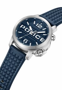 Marinblå klocka med en strukturerad silikonrem, silverfärgad rostfri stålkapsel, stora vita siffror och en tydlig "POLICE"-logotyp på urtavlan.