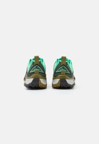 Groene en zwarte sportschoenen met een gestructureerde bovenkant, contrasterende veters, een trekband en een robuuste zool met een opvallend profiel.