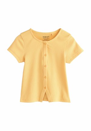 Tricou galben cu mâneci scurte, cu striații, cinci nasturi în față și o ușoară deschizătură triunghiulară în partea de jos, în centru.